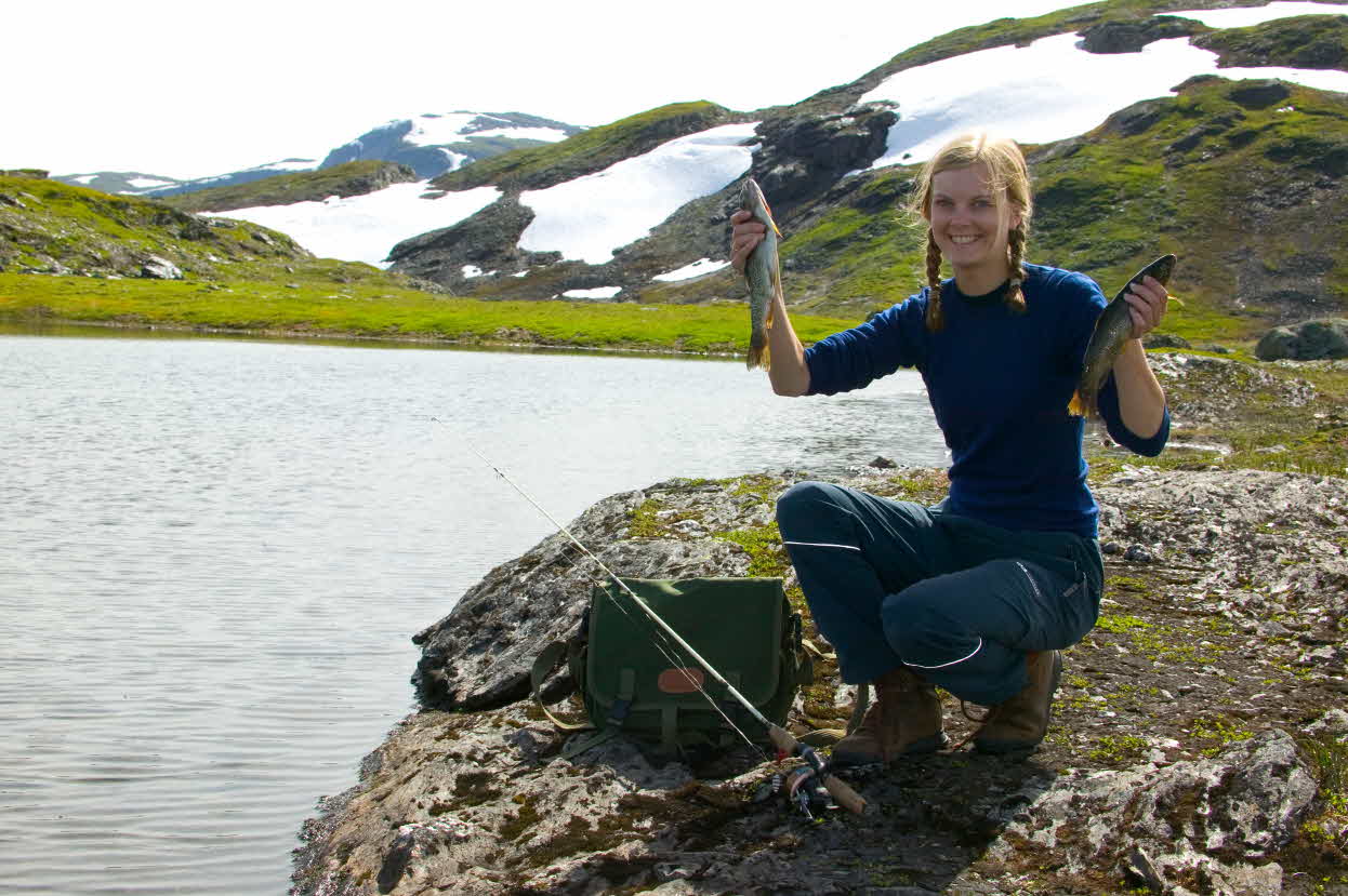 En tenåringsjente holder opp to ørret ved et fjellvann på Vikafjell ved Myrkdalen