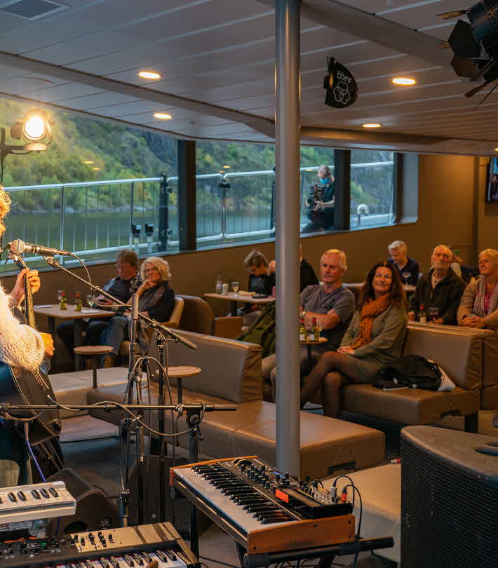 Frida Ånnevik med gitar og konsertgjester som ser på om bord på elektrisk båt
