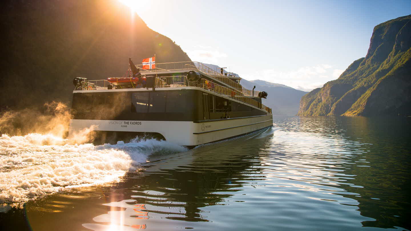 Гибридное судно Vision of The Fjords плывет по Нерёй-фьорду, вид сзади