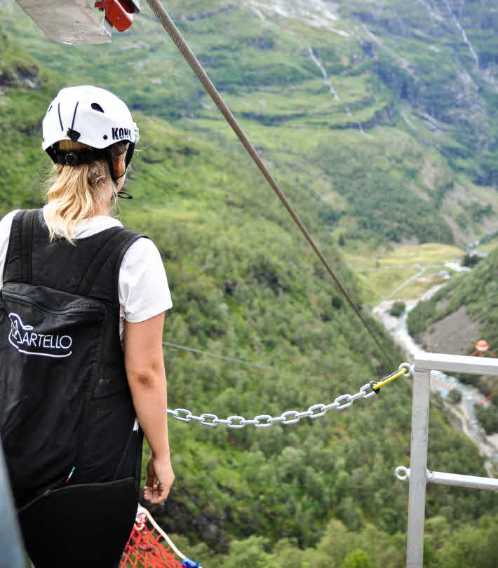 Person 'flyg' nedover Flåm Zipline med svingane og fossane i Myrdalsberget som bakgrunn