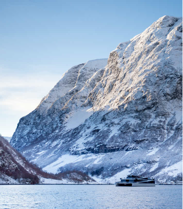 Elektrisk katamaran seglar på Nærøyfjorden ein kald, fin vinterdag