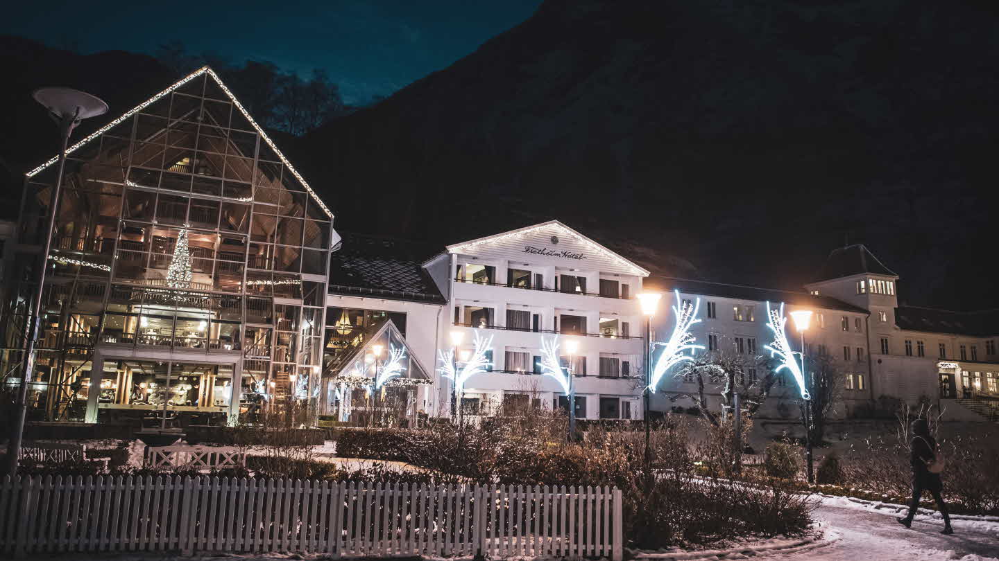Ein person går mot Fretheim Hotel som er pynta med julebelysning og juletre