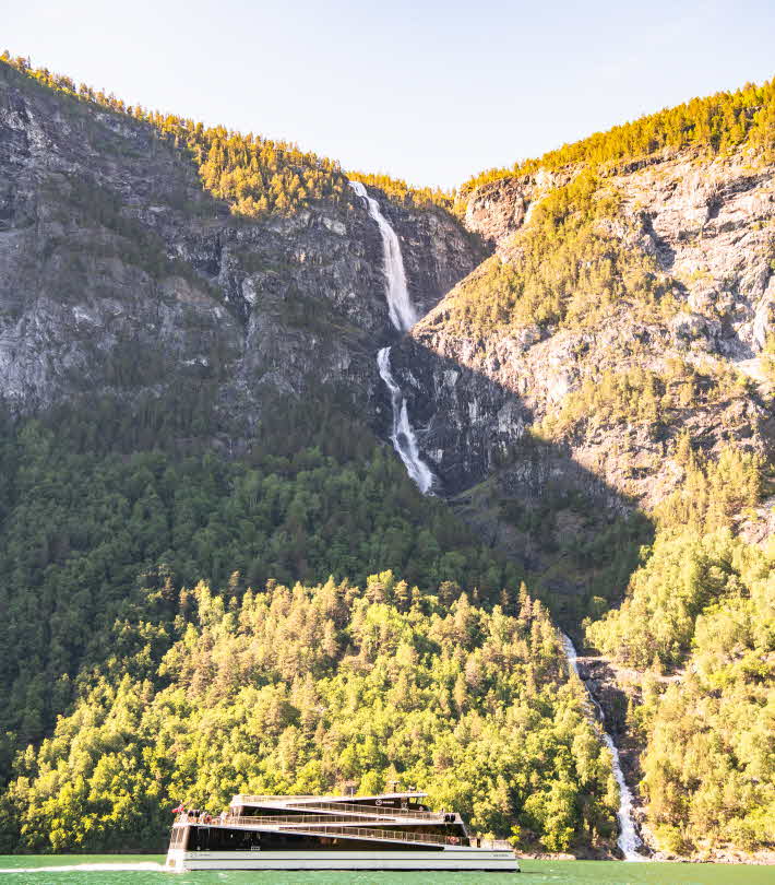Туристическое судно Future of The Fjords проплывает по Нерёй-фьорду мимо водопада Сагфоссен