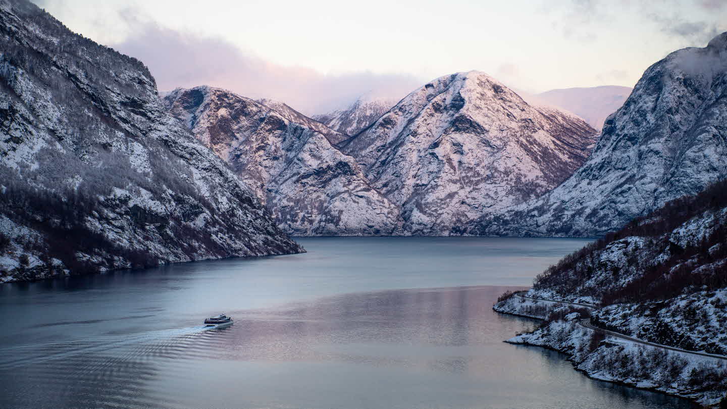 Future of The Fjords omringa av snøkledde fjell på Aurlandsfjorden