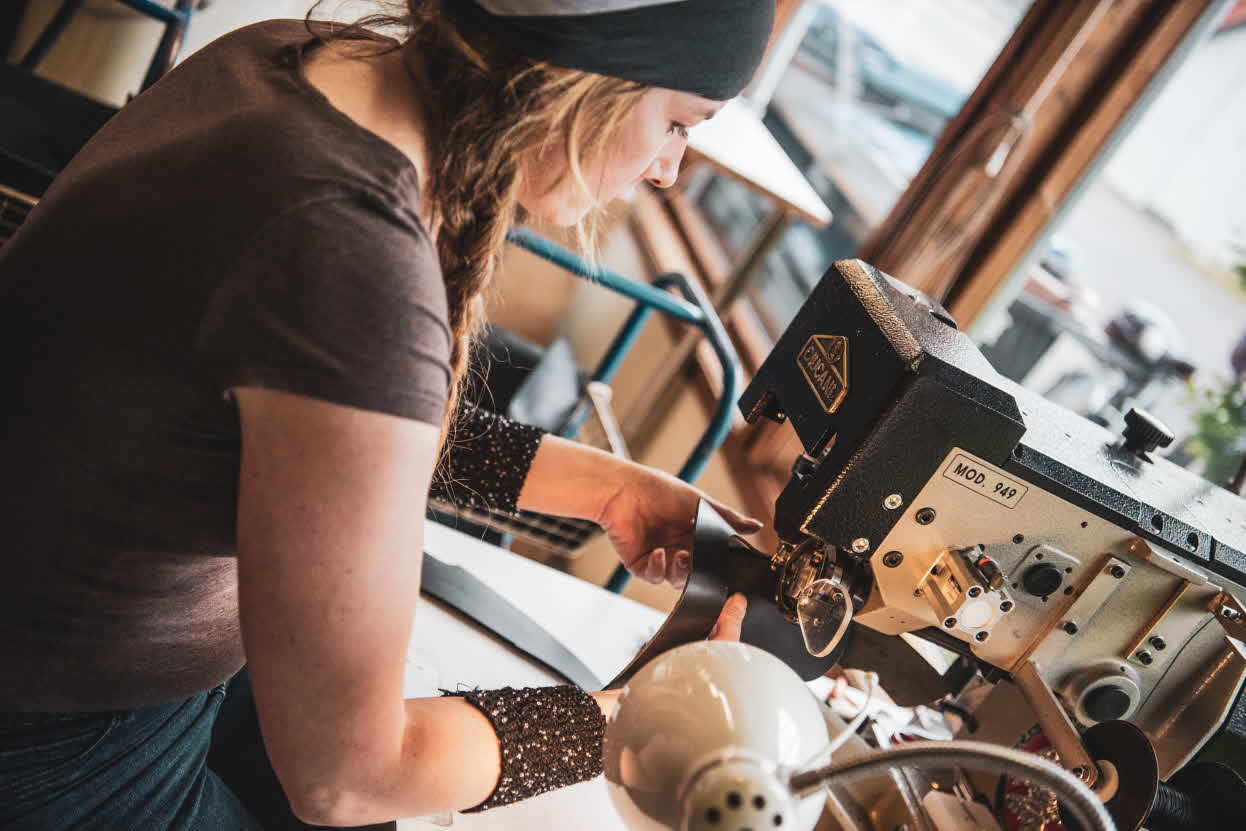 A female shoemaker sitting by a sewing machine at Aurland shoe factory