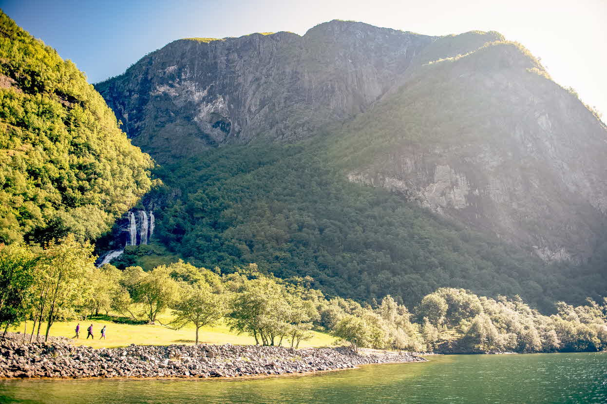 Turgåere på den gamle kongevegen ved Nærøyfjorden med foss i bakgrunnen