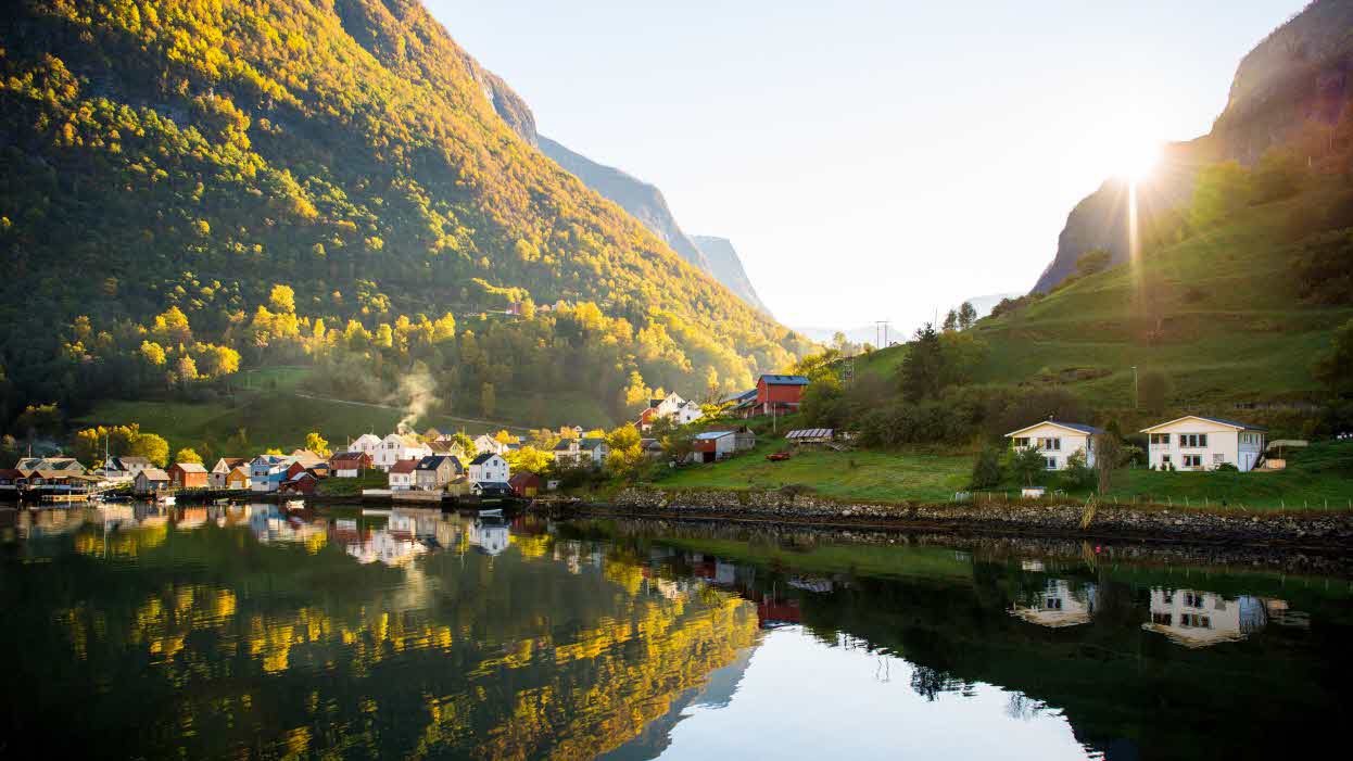 Undredal med gammel trehusbebyggelse og to nyere hus ved fjordkanten