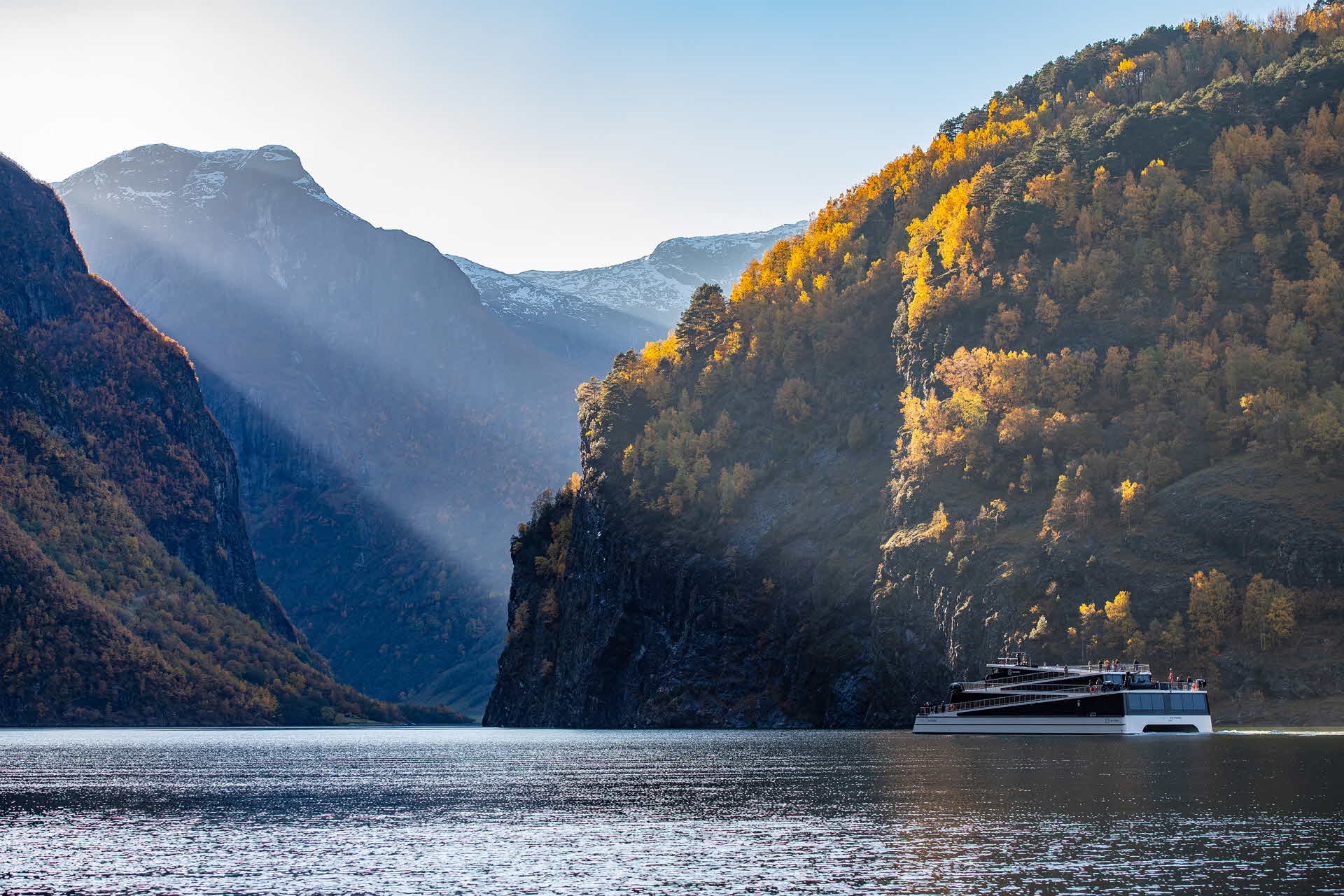 Panoramic view of woman standing on outside deck Vision of The Fjords overlooking the UNESCO listed Naeroyfjord in summer