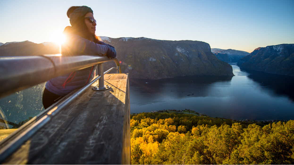 Kvinne nyter solnedgangen over Aurlandsfjorden fra Stegastein