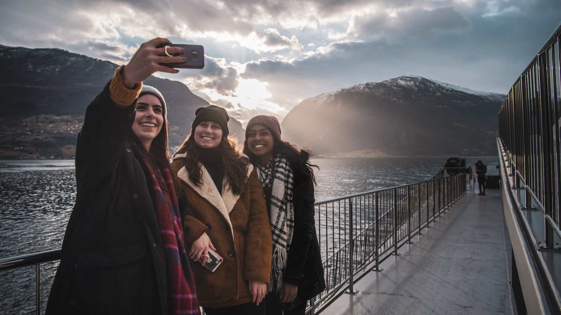 Panorama view of woman standing in the front and middle of Future of The Fjords sailing through Naeroyfjord in summer